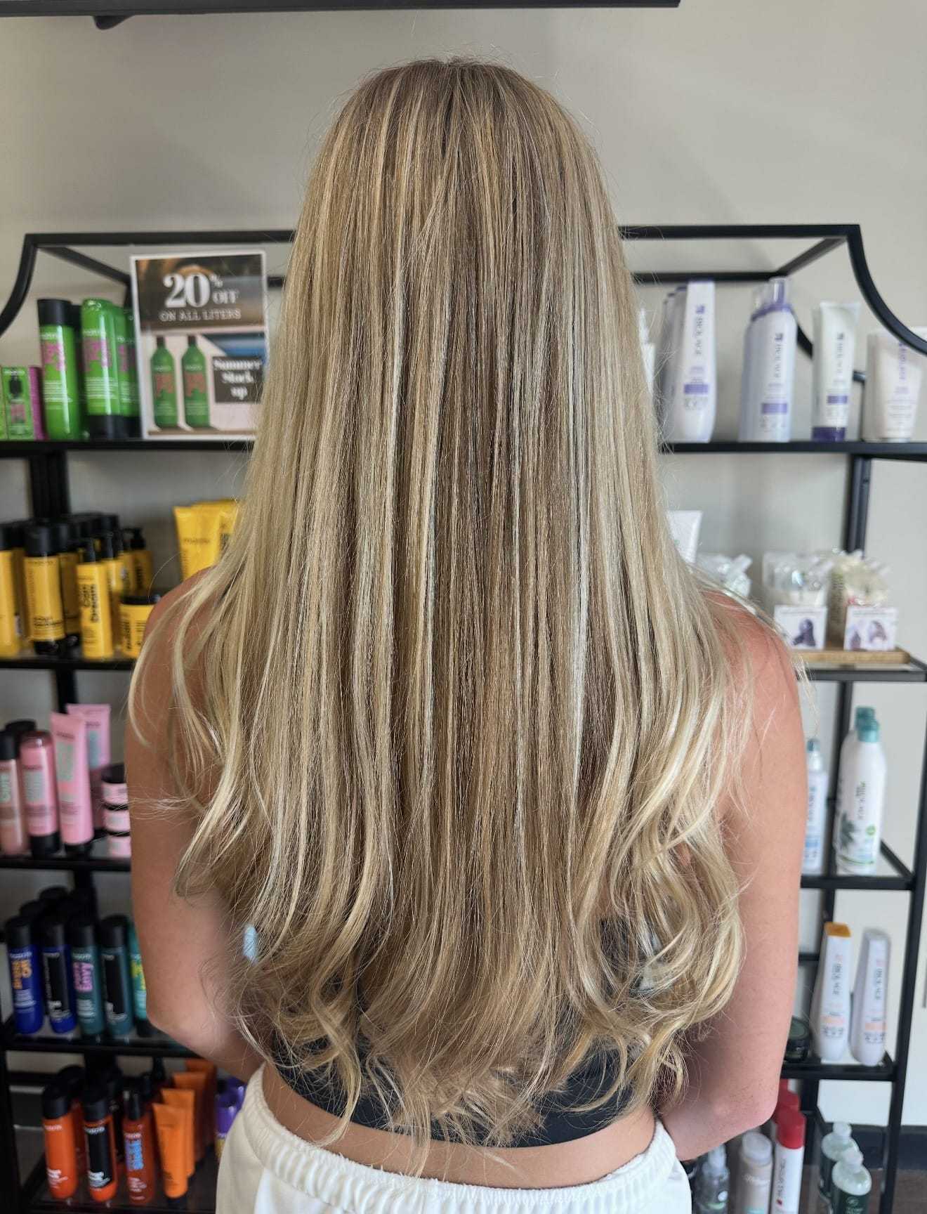 Long, straight blonde hair viewed from the back in a salon setting.