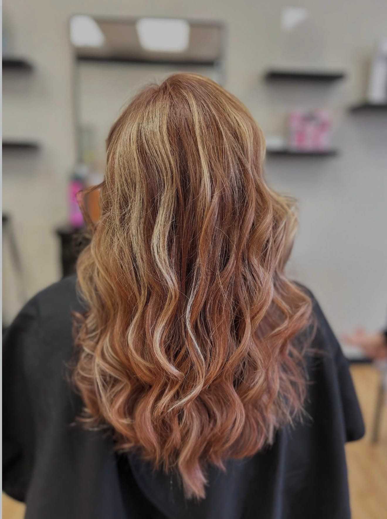 Wavy brown hair with blonde highlights in a salon setting.